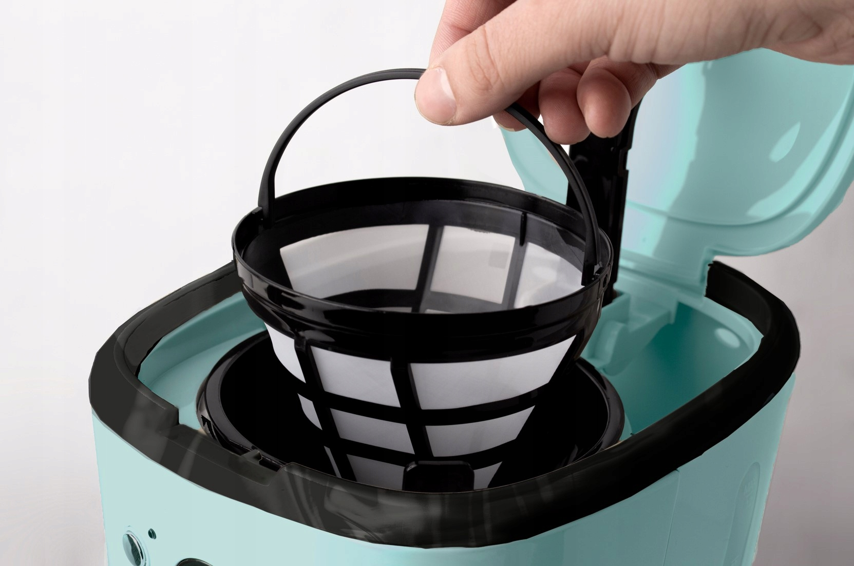 Ręka wkładająca kosz filtra do kawy do ekspresu.