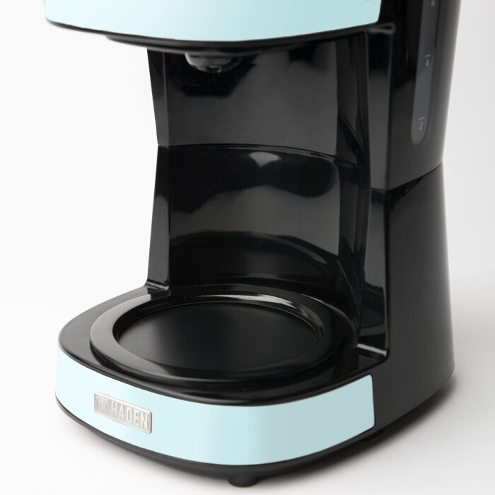 Zbliżenie obudowy ekspresu do kawy. Czarny z niebieskimi akcentami i logo Haden.