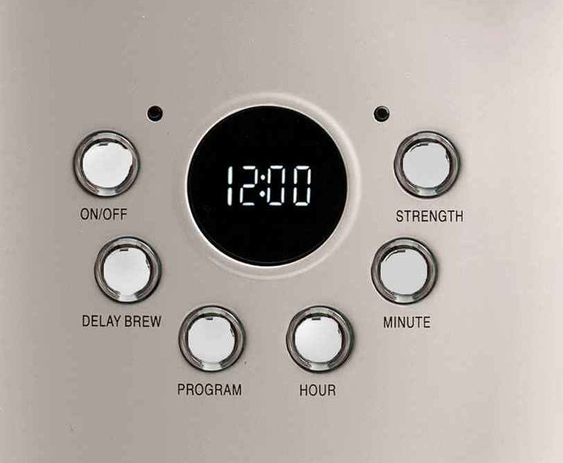 Zbliżenie panelu sterowania ekspresu do kawy z przyciskami i wyświetlaczem cyfrowym pokazującym 12:00.