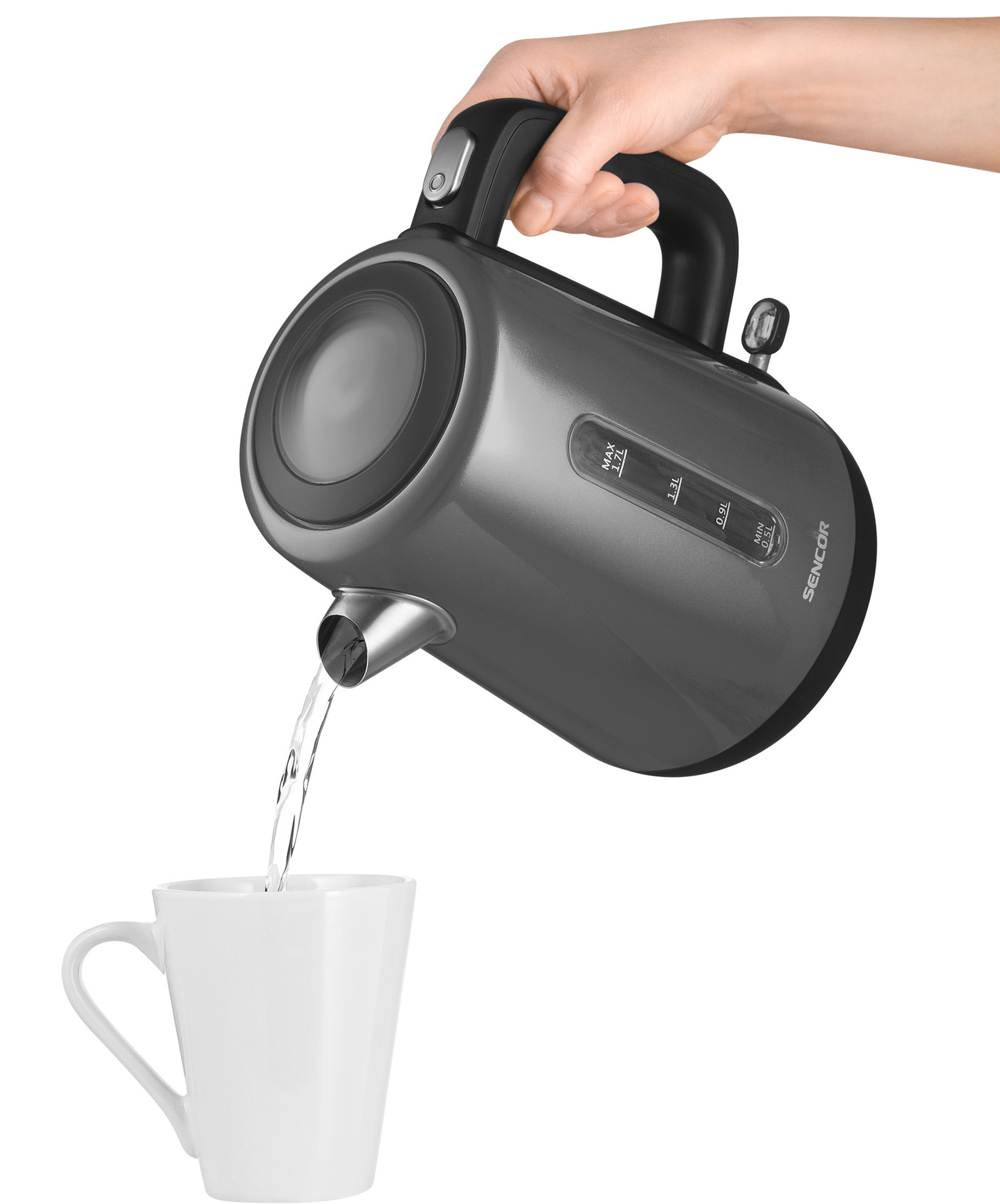 Ręka nalewająca wodę z szarego czajnika elektrycznego do białego kubka. Białe tło.