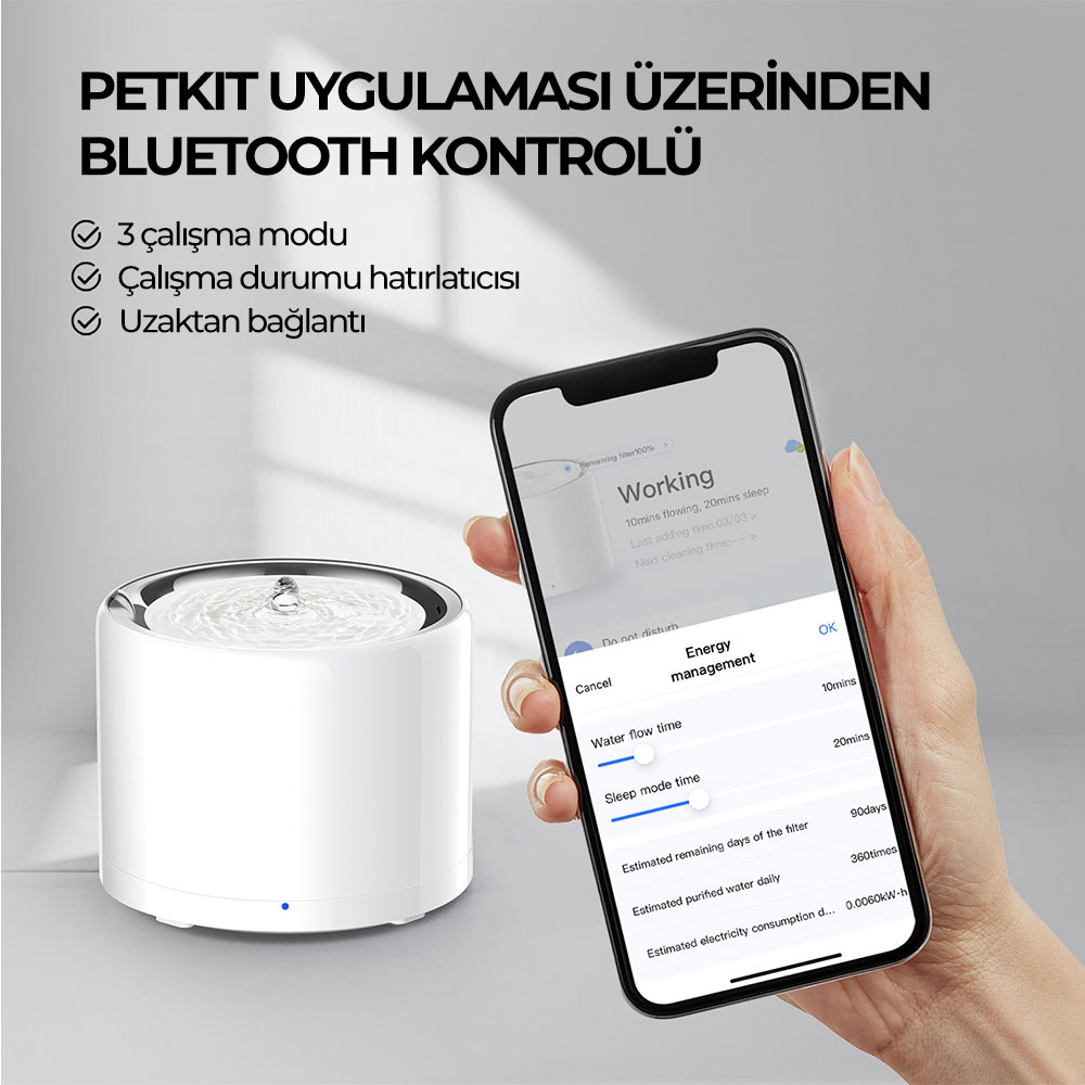 Bir el, evcil hayvan çeşmesi uygulaması gösteren bir telefon tutuyor. Solda akan su ile beyaz bir çeşme var. Türkçe metin.