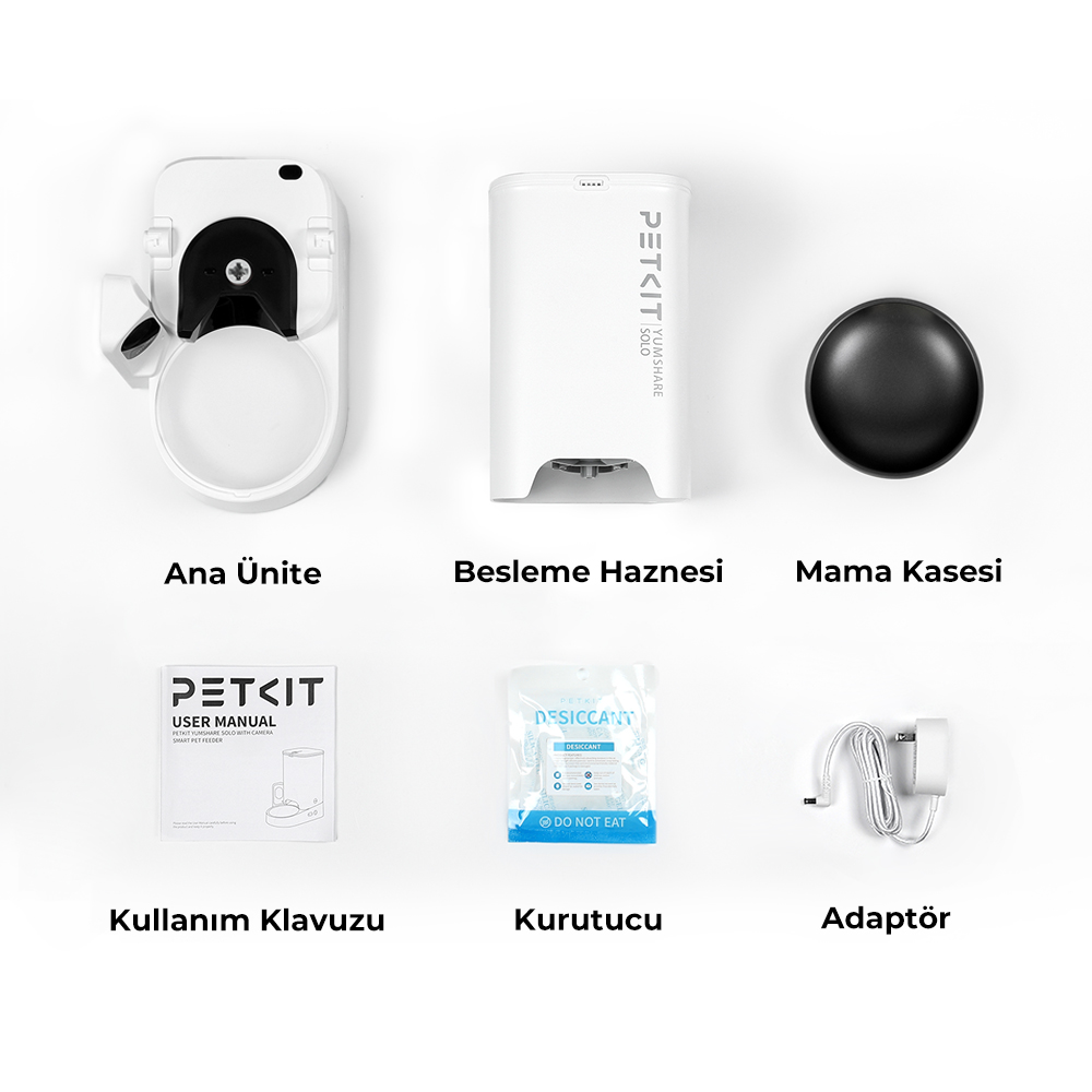 Beyaz evcil hayvan besleyici bileşenleri: ünite, mama kabı, kap, kılavuz, kurutucu paket ve adaptör. Hepsi beyaz bir yüzeyde.