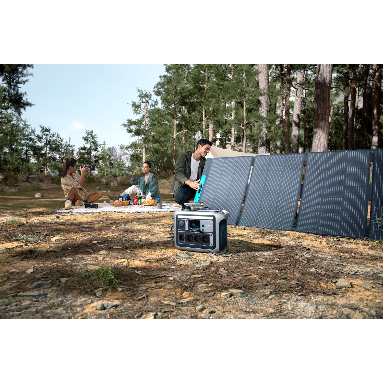 Three people camping with solar panels and a power station in a forest. One person uses a camera. Picnic blanket on the ground.