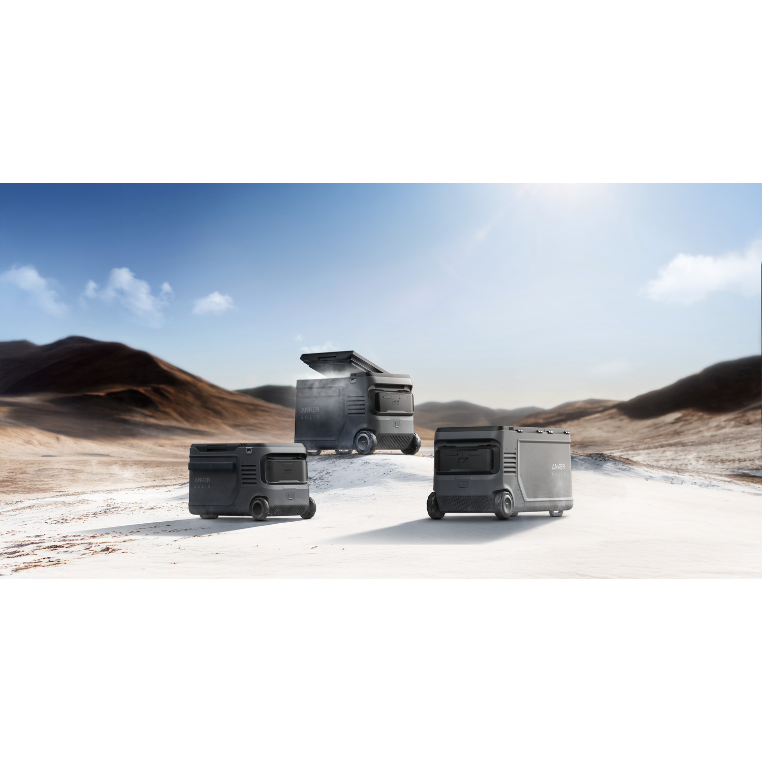 Three gray Anker Solix units on a snowy landscape under a blue sky. One has an open top.