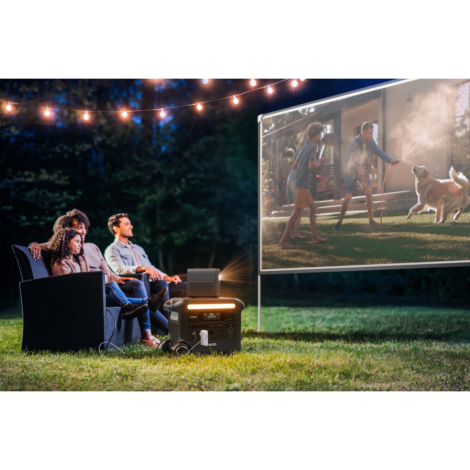 Famille regardant un film en plein air. Projecteur et centrale électrique au premier plan. Film montre un homme, un enfant et un chien.