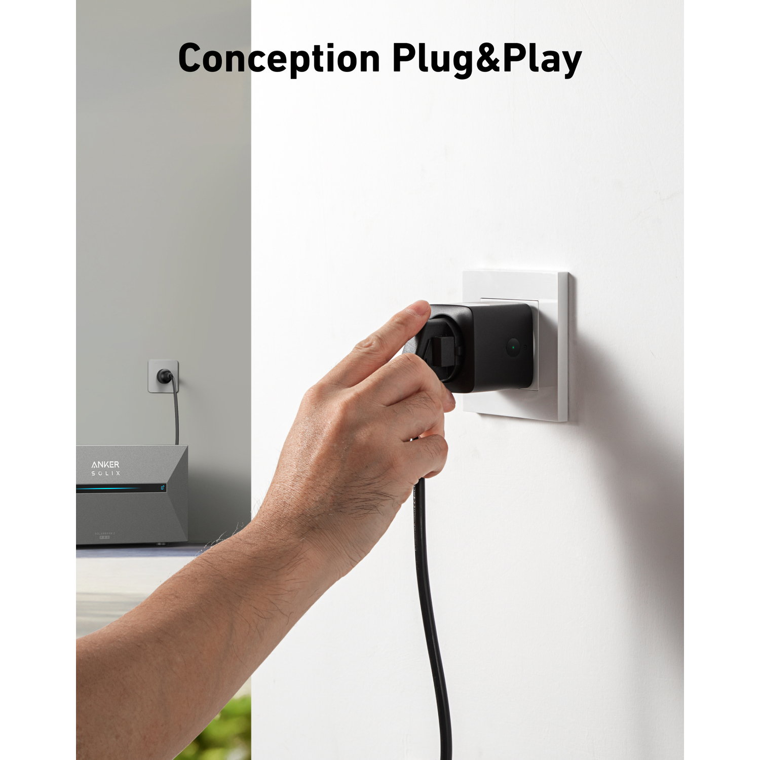 Hand inserting a black plug into a white wall socket. Anker device and another socket are in the background.