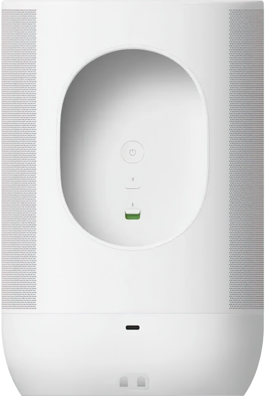 Biały głośnik z zaokrągloną górą, wklęsłym owalem, przyciskiem zasilania i zielonym światłem. Perforowane panele boczne i płaska podstawa.