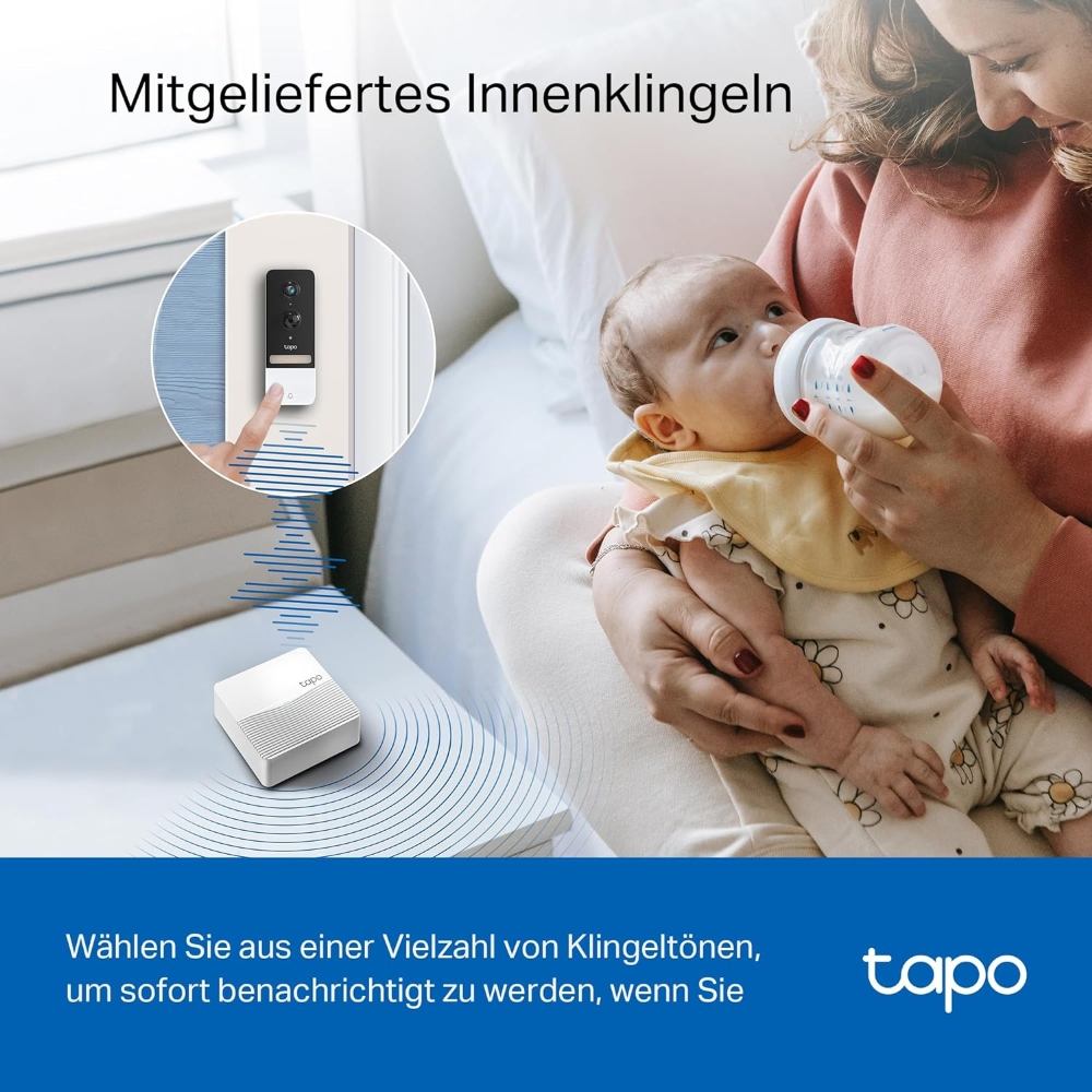 Eine Frau füttert ein Baby mit einer Flasche. Eine Türklingel und ein weißer Lautsprecher sind im Hintergrund zu sehen.