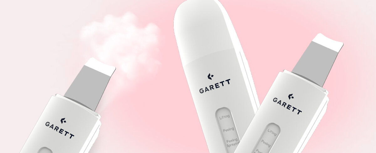 Trzy białe urządzenia do pielęgnacji skóry GARETT na różowym tle. Każde urządzenie ma srebrny, szpatułkowaty koniec.