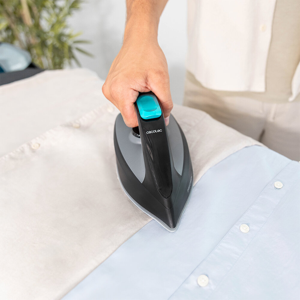 Osoba prasuje błękitną koszulę. Żelazko jest czarne i szare z turkusowym uchwytem. Koszula jest na jasnej powierzchni.