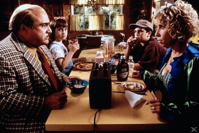 Familie am Tisch. Mann im Jackett, Mädchen mit Schleife, Junge mit Mütze isst, Frau mit Lockenwicklern. Essen und Toaster.