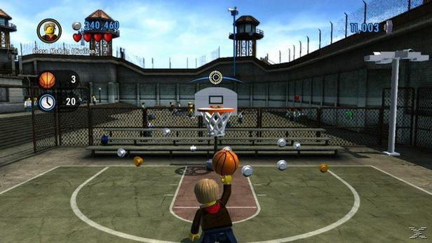 Postać Lego zaraz rzuci piłkę do kosza na dziedzińcu więzienia. Tło z ludźmi, wieżami strażniczymi i ogrodzeniem.