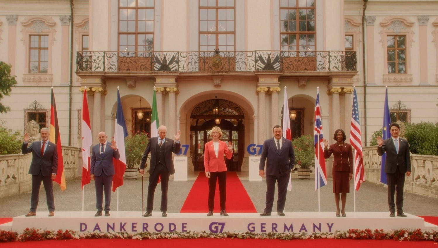 G7-Führer winken vor einem Palast mit Fahnen. Die Szene spielt sich auf rotem Teppich ab. Text: Dankerode, G7, Deutschland.