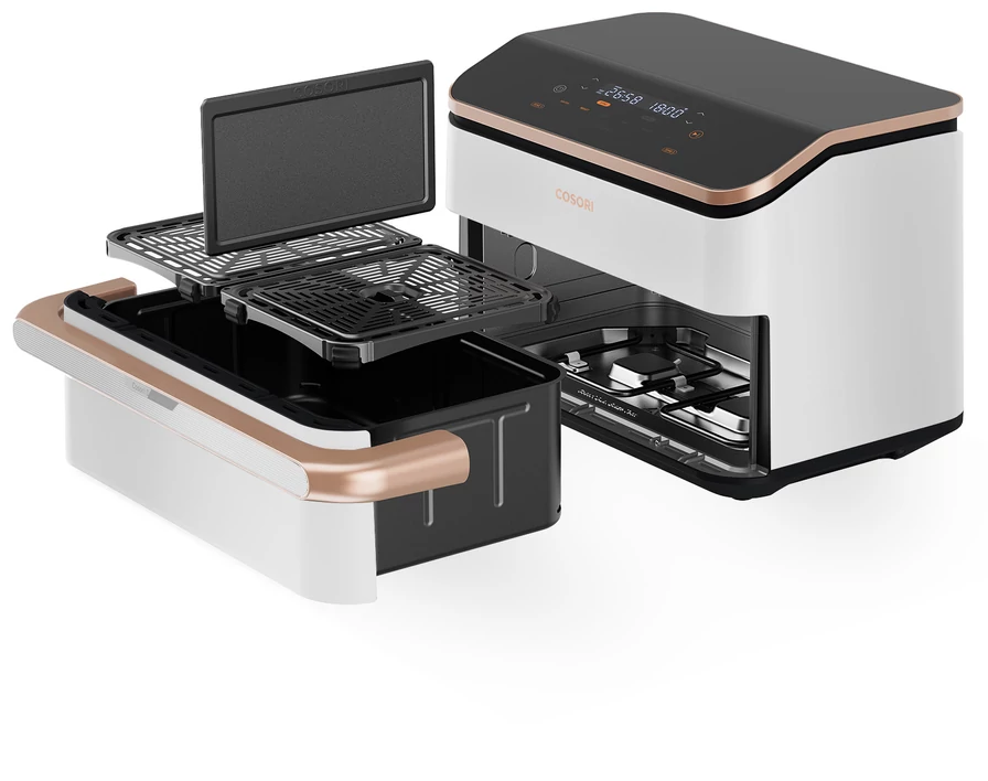 Levegősütő kivehető alkatrészekkel. Fekete belső, fehér és rózsaarany külső. Grill és tálcák láthatók. Digitális kijelző felül.