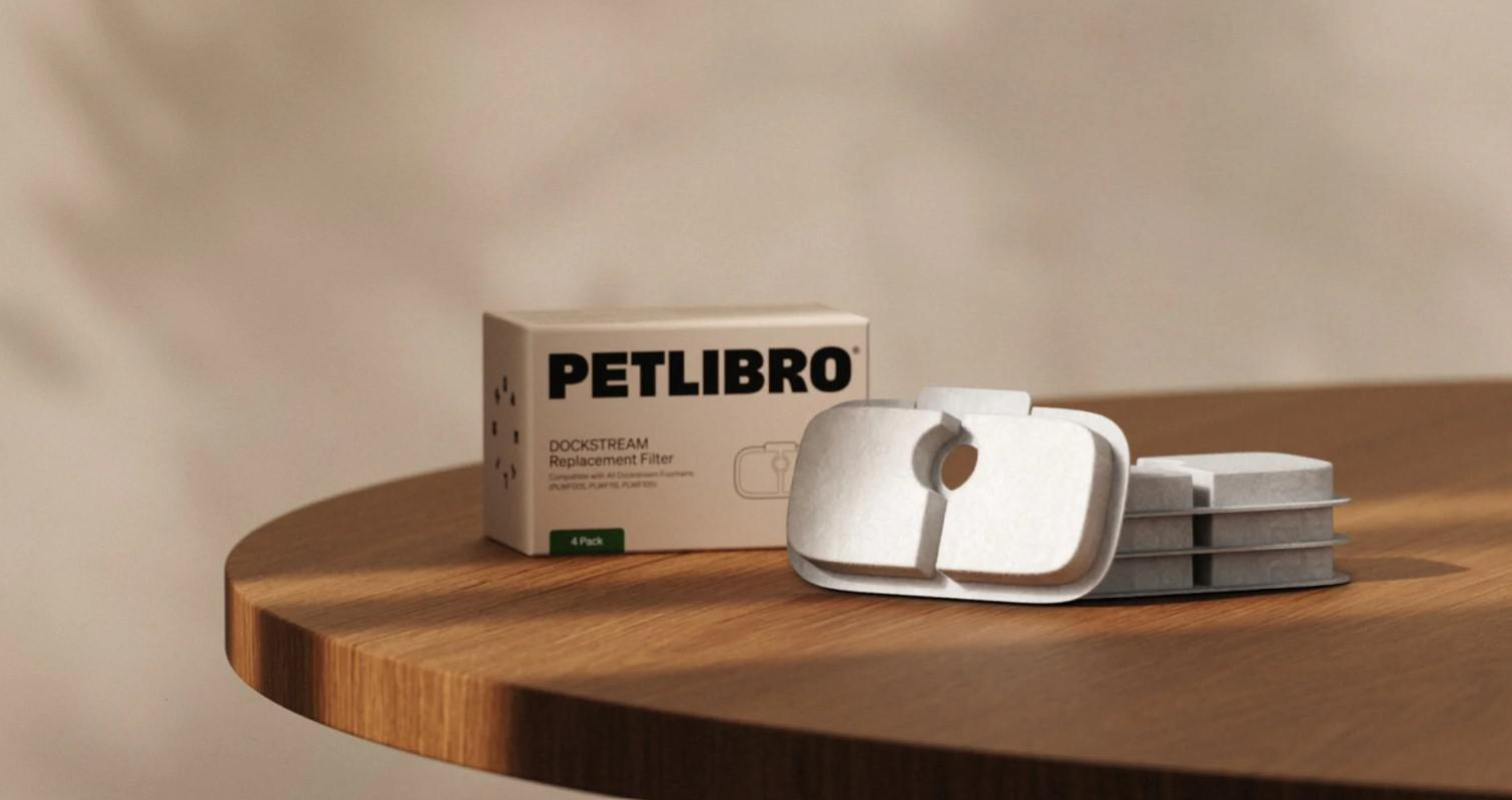 Petlibro Dockstream Ersatzfilterbox und Filterstücke auf Holzoberfläche, heller Hintergrund. Beige und weiße Farben.