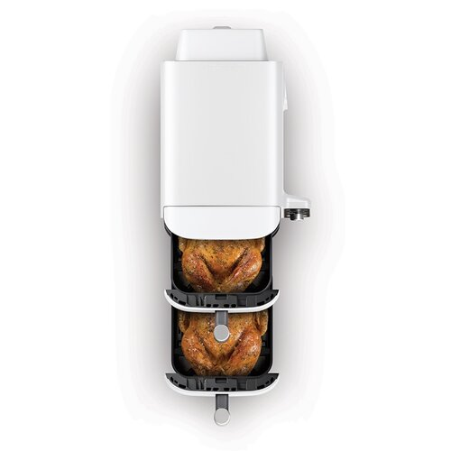 Biała frytkownica powietrzna z dwoma ugotowanymi kurczakami w środku. Widok z góry na urządzenie, na białym tle.