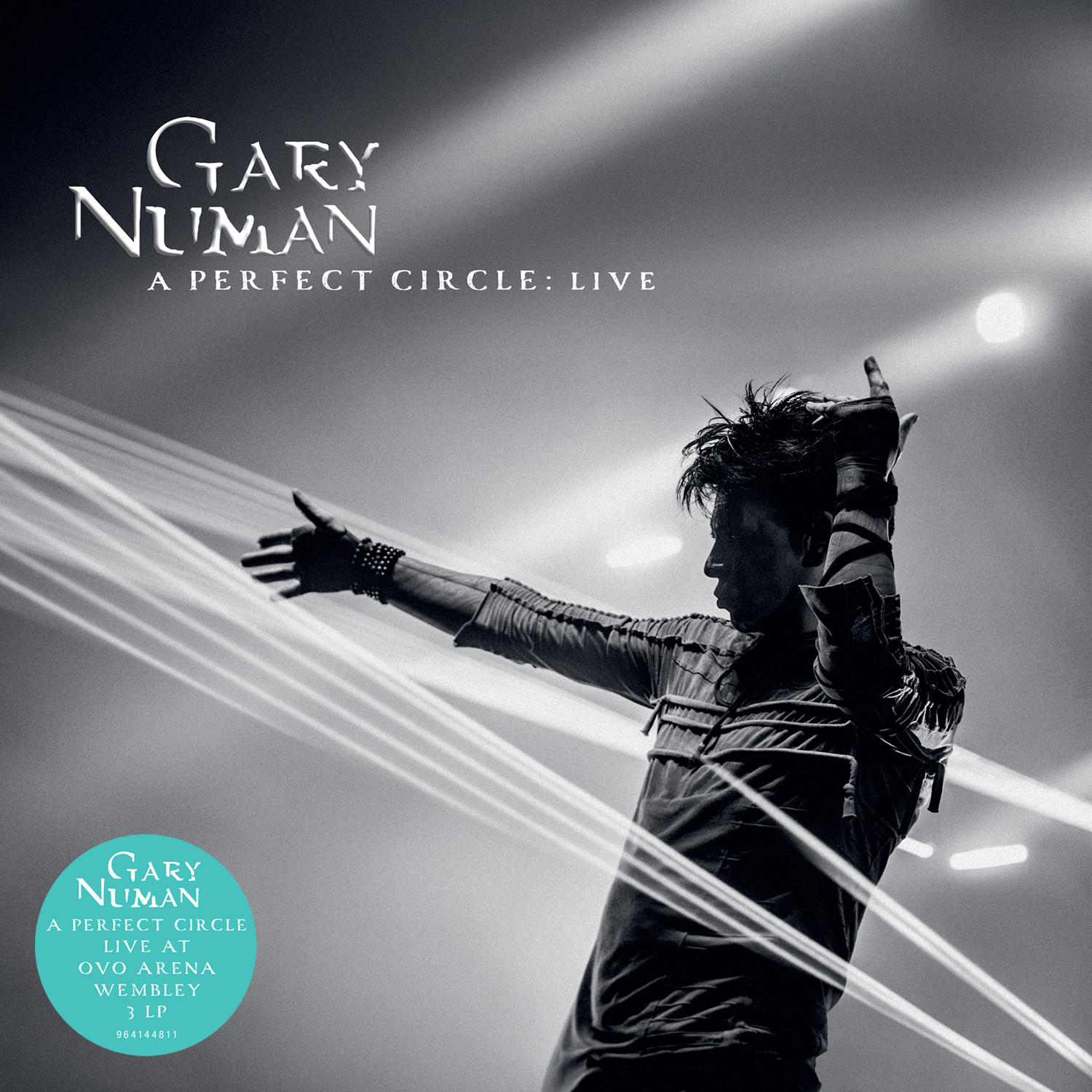 Gary Numan auf der Bühne, Arme erhoben, performt. Albumcover, "A Perfect Circle: Live". Schwarzweiß. Text oben und unten.