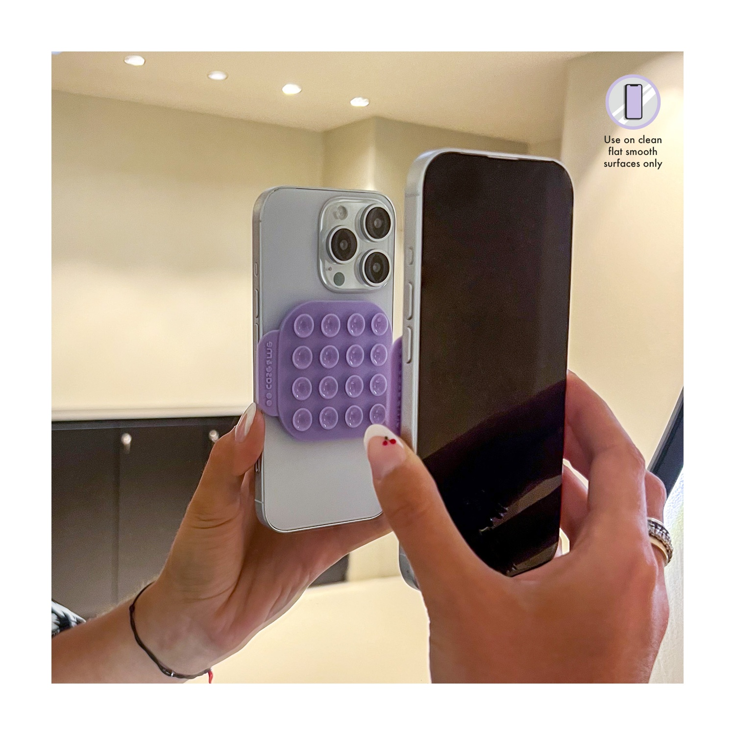 Una persona tiene in mano due iPhone. Uno ha un'impugnatura viola, lo schermo dell'altro è rivolto verso la fotocamera. Un cartello dice: "Utilizzare solo su superfici pulite e lisce."