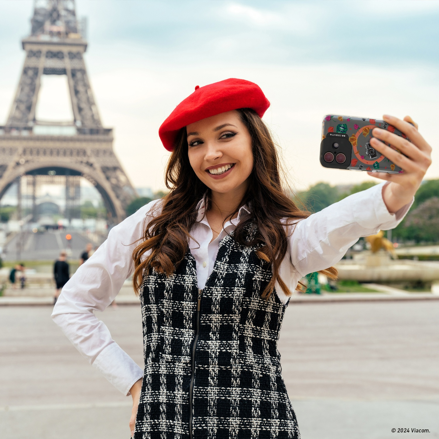 Donna con basco rosso fa un selfie davanti alla Torre Eiffel. Indossa un vestito bianco e nero.