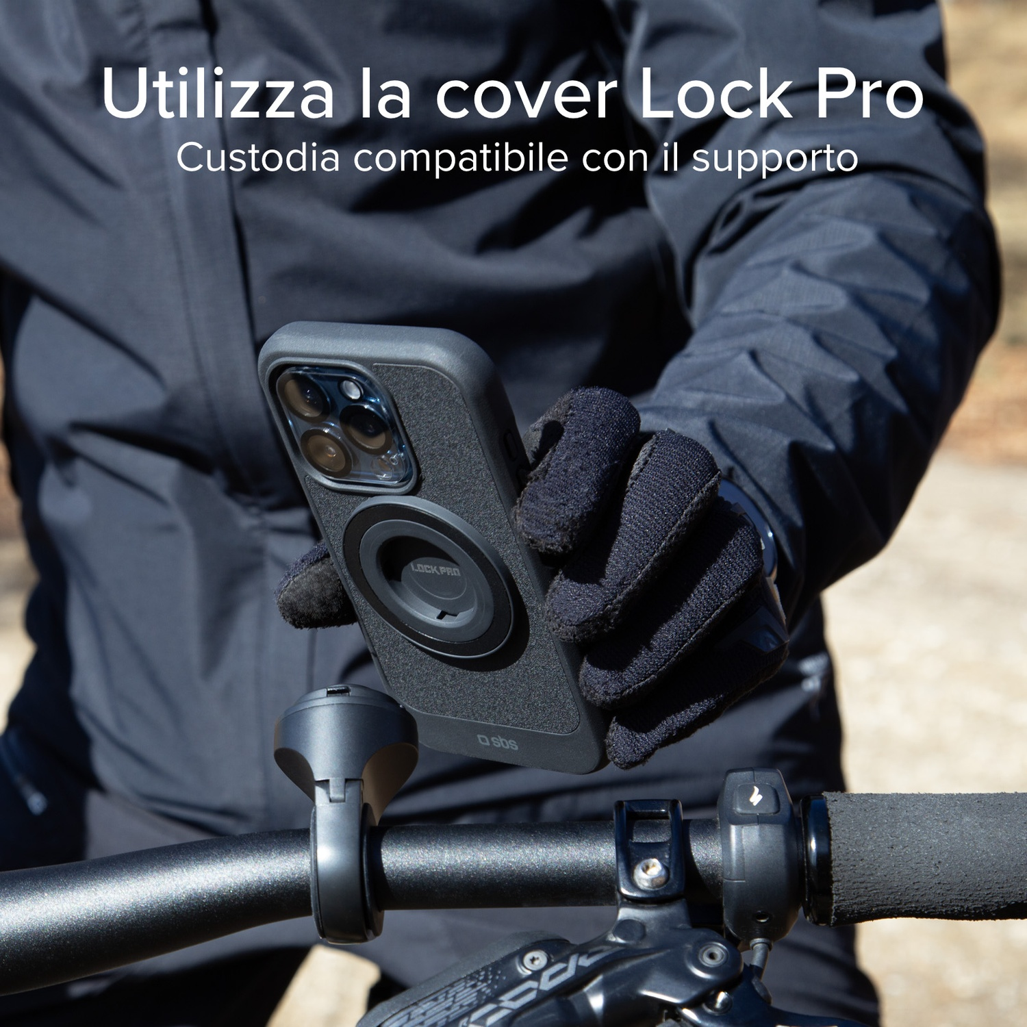 Una persona con guanti neri tiene in mano un telefono con una custodia Lock Pro. Il telefono è montato sul manubrio di una bici.