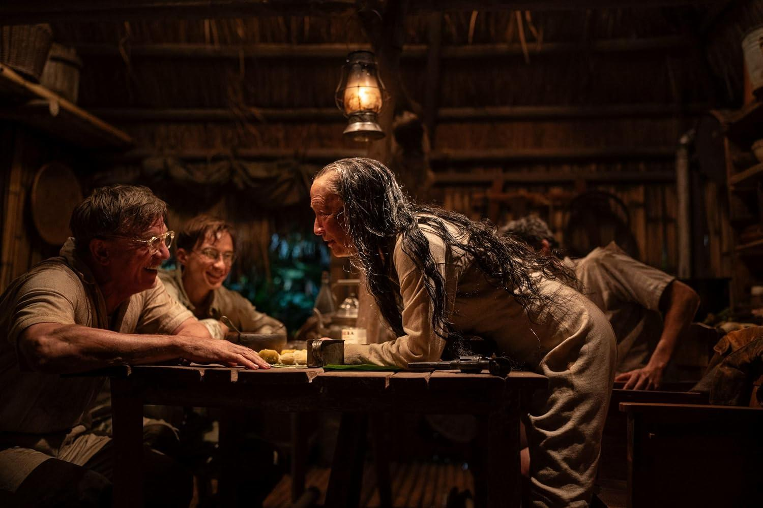 Menschen sitzen an einem Tisch in einem dunklen Raum unter einer Laterne.