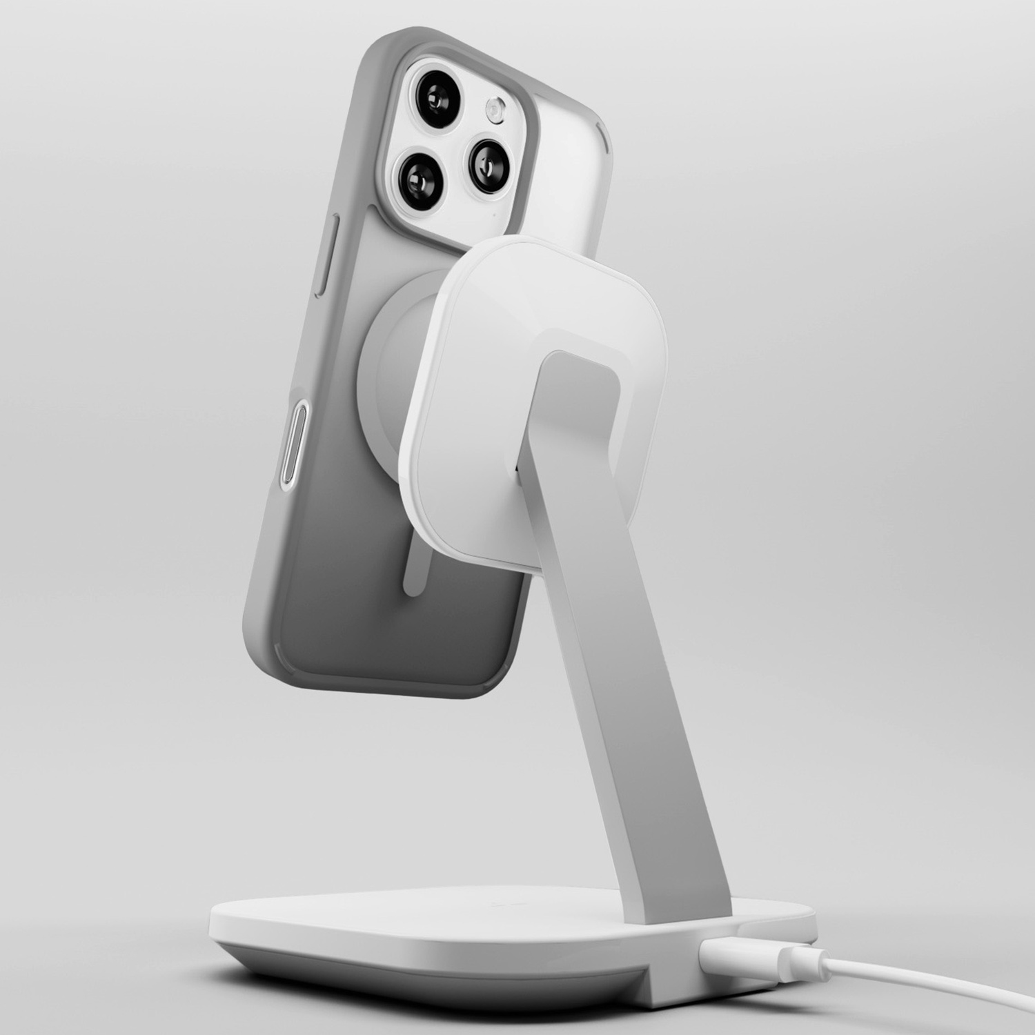 Un telefono grigio con custodia bianca è su un supporto bianco con cavo di ricarica, su sfondo grigio.