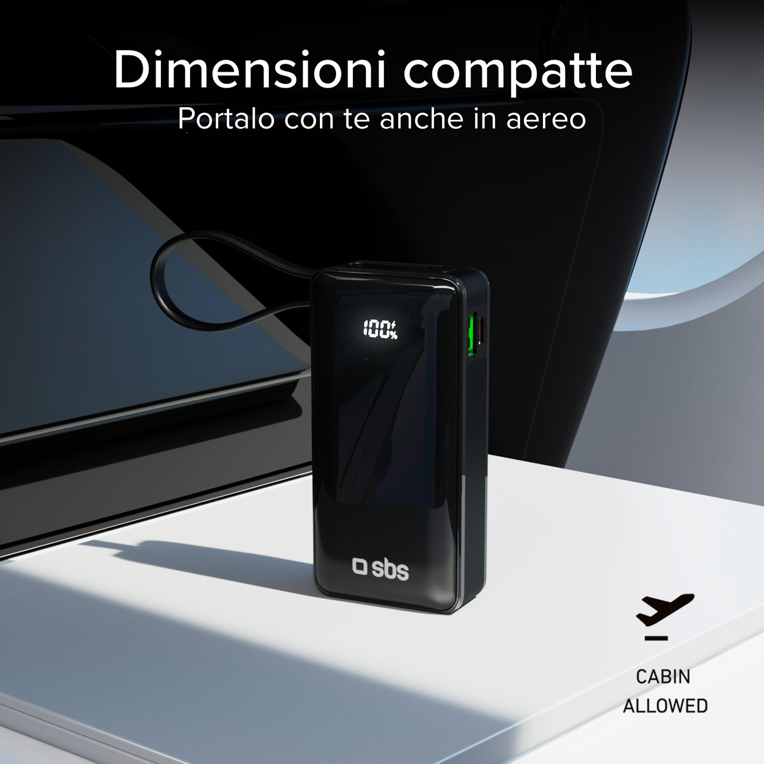 Power bank nera su superficie bianca con testo 'Cabina consentita'. Finestrino aereo sullo sfondo.