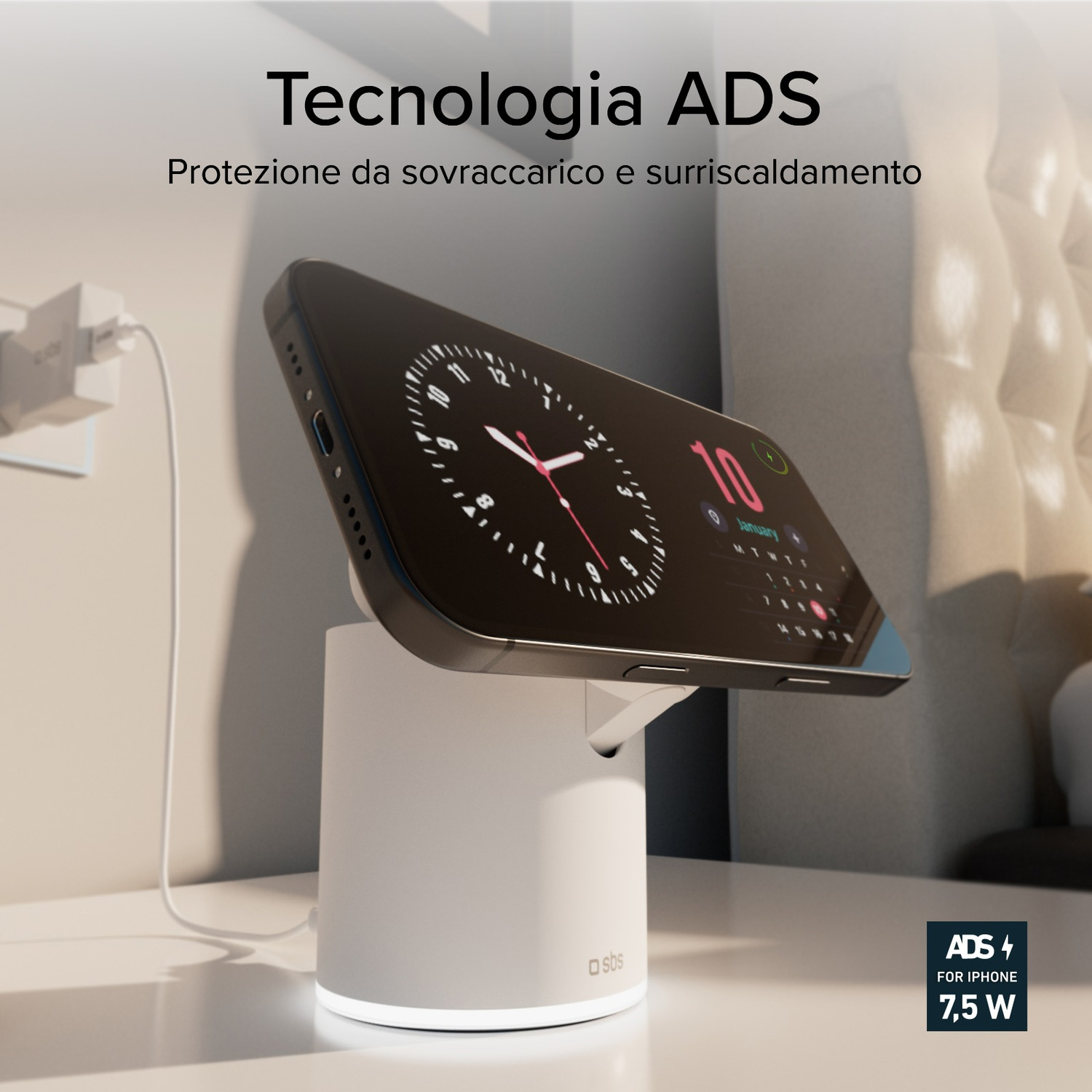 Telefono in carica su supporto bianco. Il telefono mostra un orologio. Lo sfondo mostra una parete e testo in italiano.