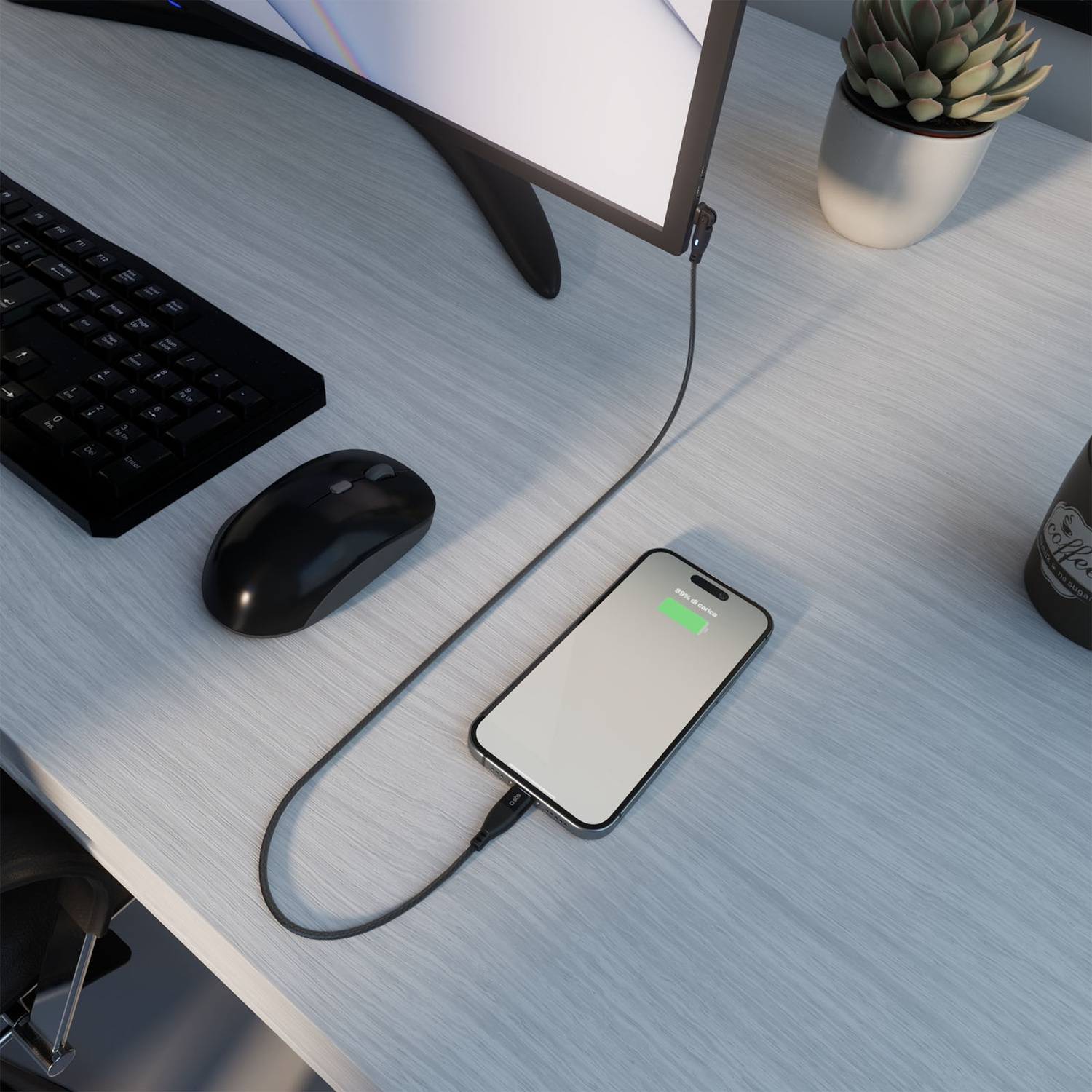 Uno smartphone in carica su una scrivania. Sono visibili anche tastiera, mouse, monitor e pianta. Il telefono è all'89% di carica.