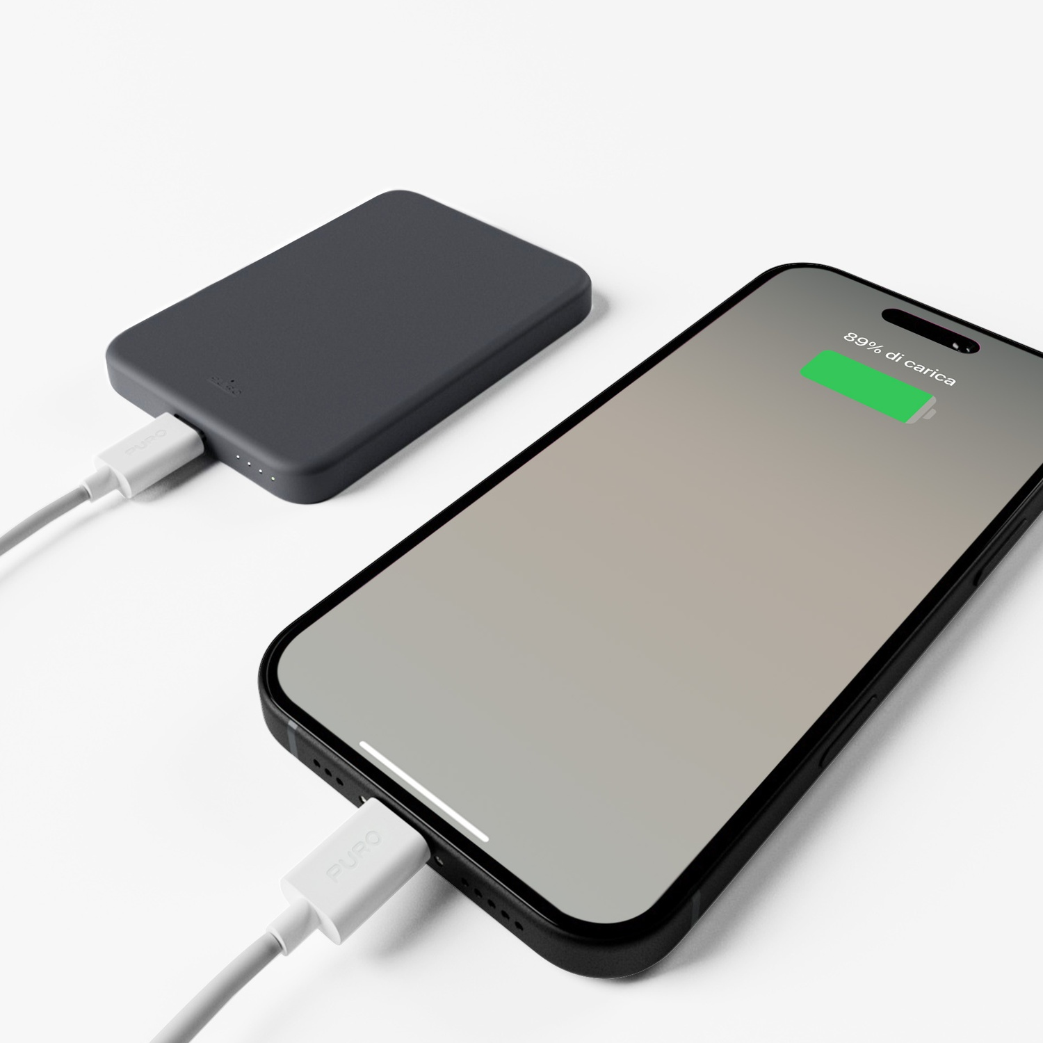 Telefono in carica con 89% di batteria, collegato a power bank grigio tramite cavo bianco. Sfondo bianco.