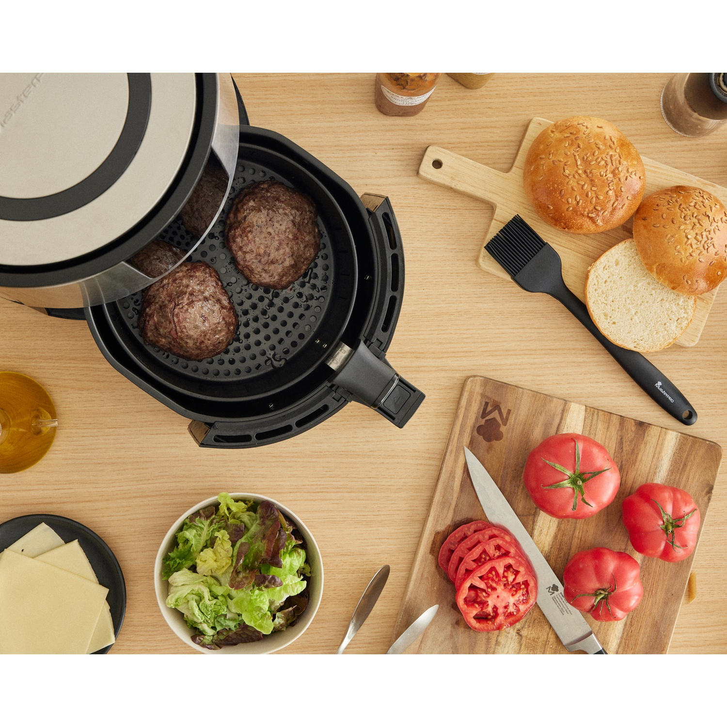 Friggitrice ad aria con hamburger, panini, pomodori, insalata, formaggio e pennello su un tavolo di legno. Ingredienti per hamburger pronti.