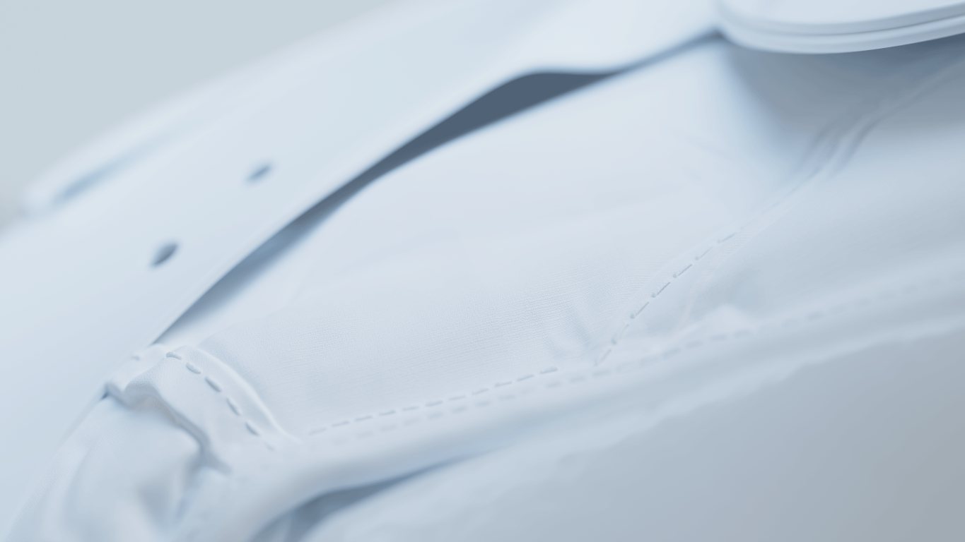 Zbliżenie białej tkaniny ze szwem i zapiętym kołnierzem. Materiał jest lekko pomarszczony i ma gładką fakturę.