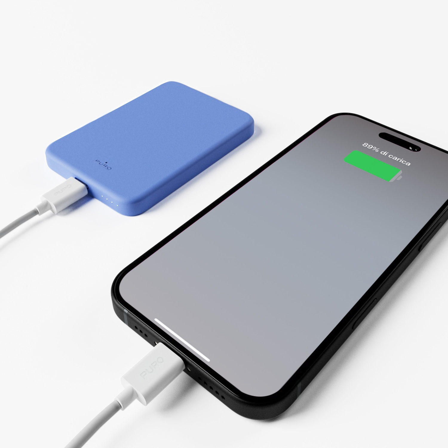 Un power bank blu carica un telefono nero. Il telefono mostra l'89% di batteria. Entrambi sono collegati con cavi bianchi.
