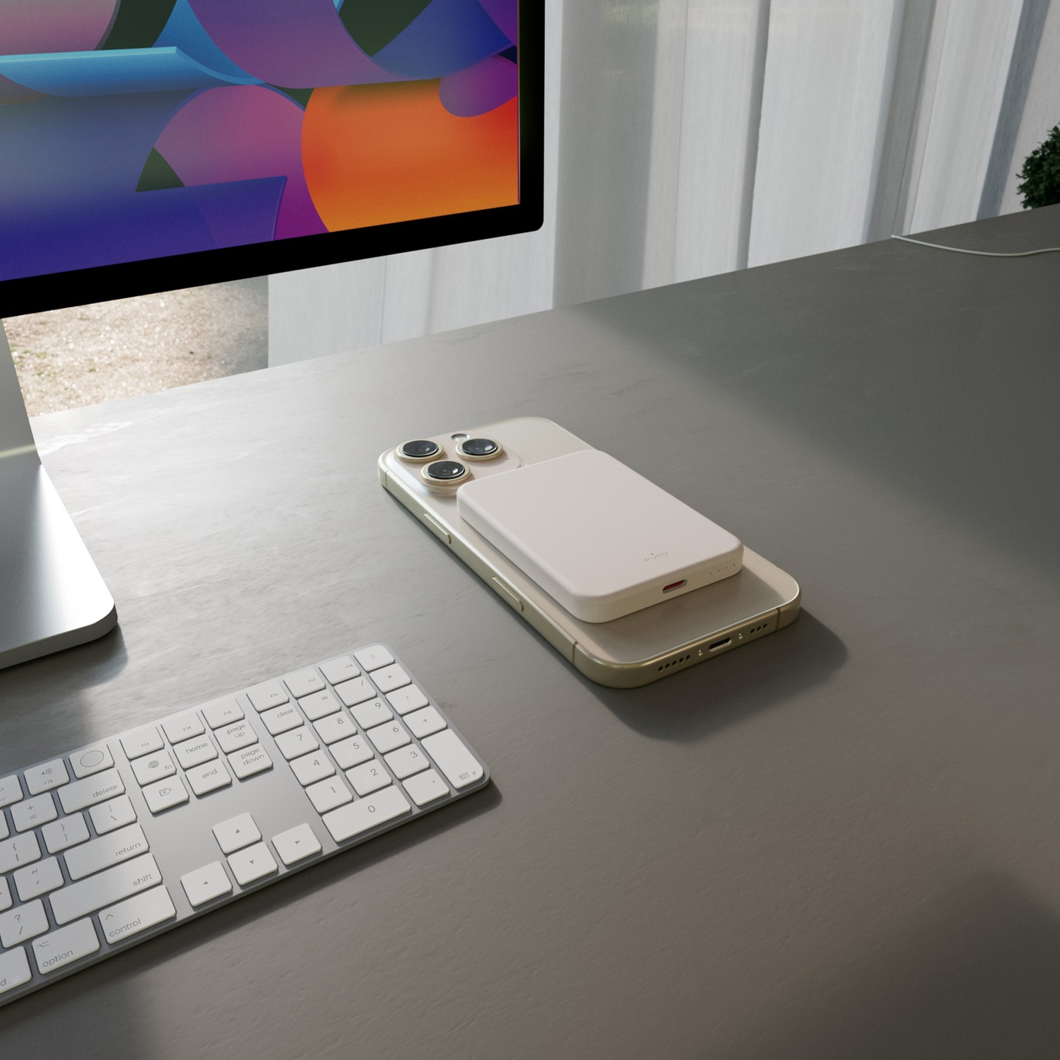 Un telefono con un caricatore bianco è su una scrivania. Una tastiera e uno schermo di computer sono anche sulla scrivania.