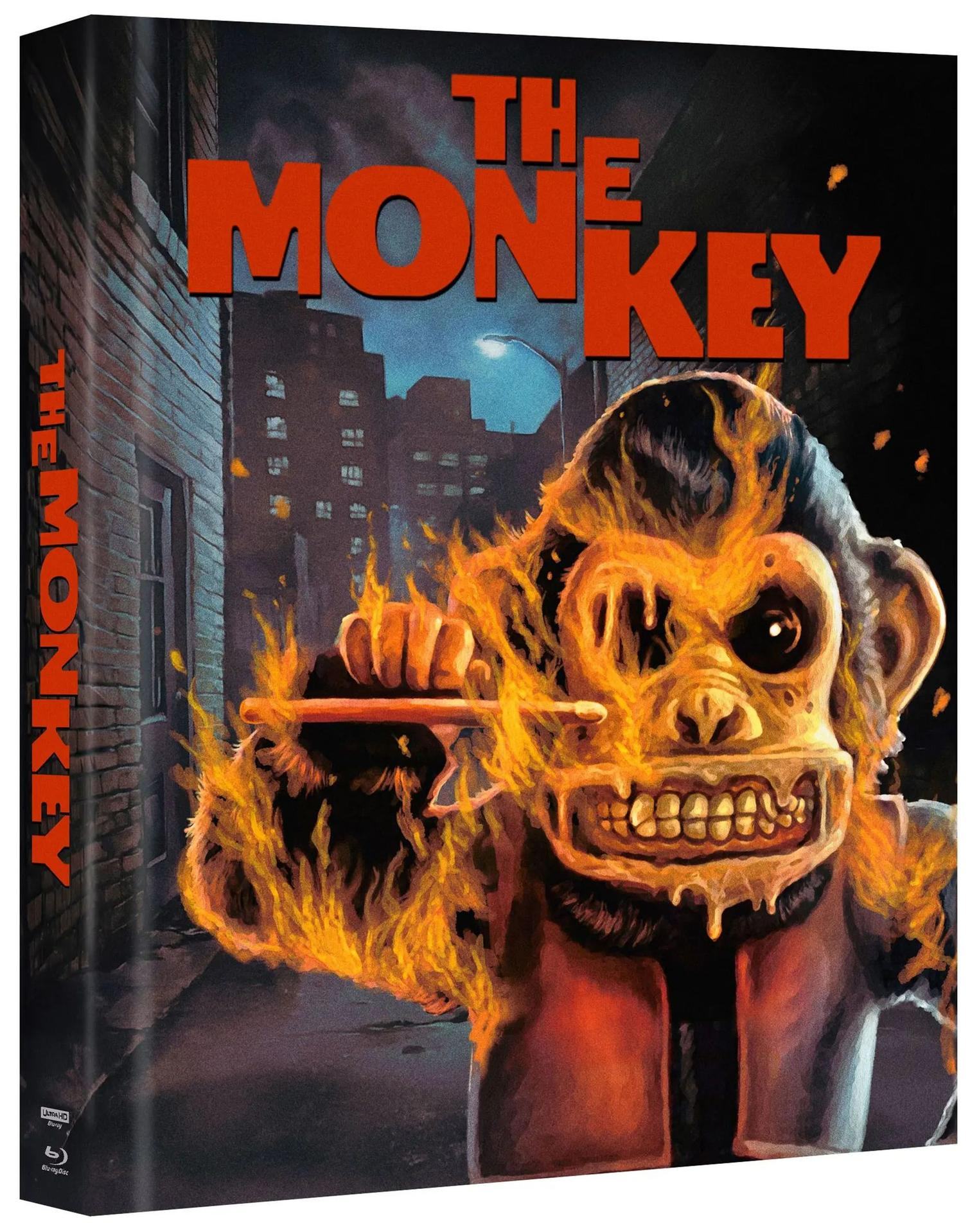 Cover-Art für "The Monkey". Ein brennender Affe hält eine Flöte in einer Gasse, Titel in Orange. Gebäude im Hintergrund.