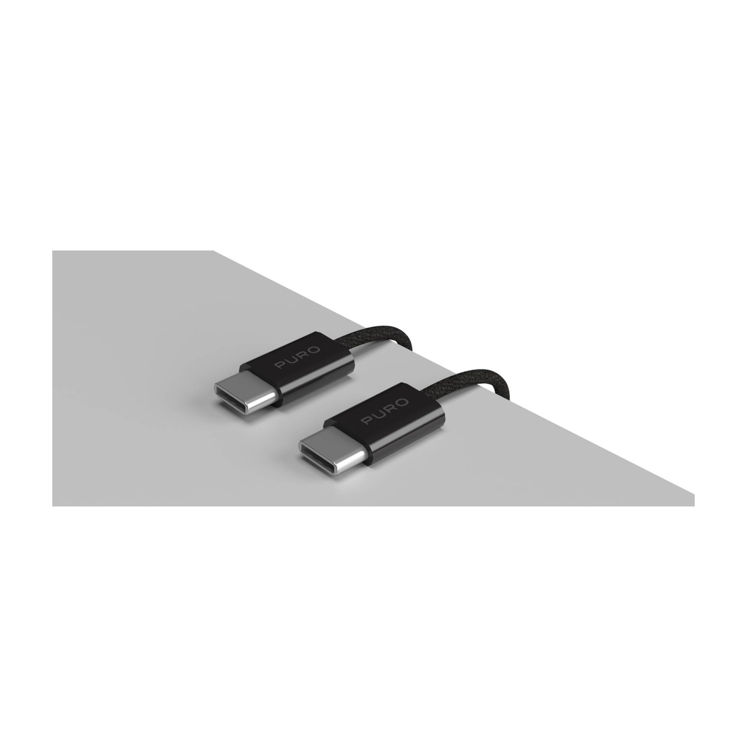 Due cavi USB-C con cavi intrecciati neri, etichettati 'PURO', su una superficie grigio chiaro. Lo sfondo è bianco.