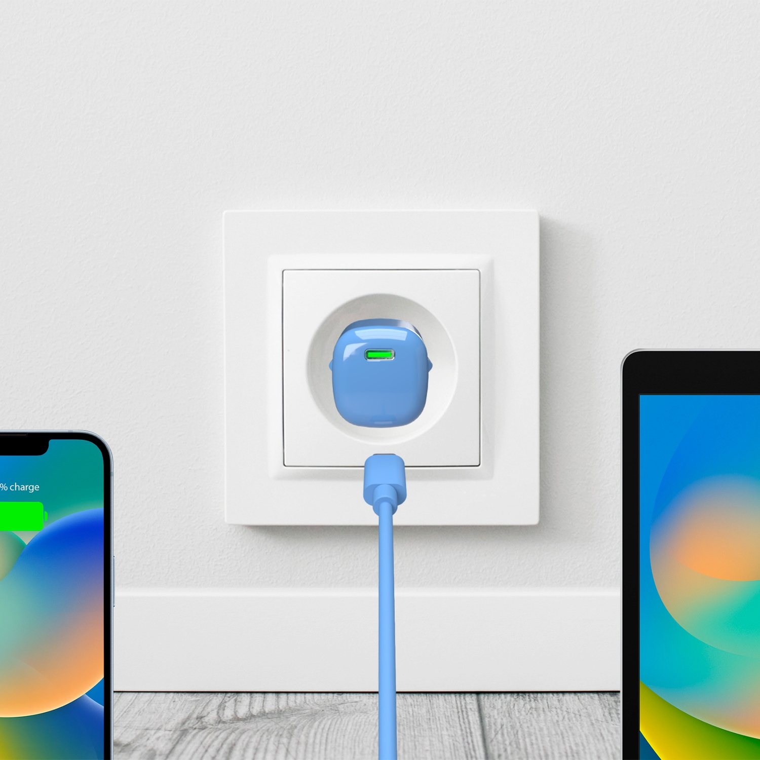 Telefono e tablet in carica. Caricatore blu collegato al muro. Indicatore di carica verde sul telefono.