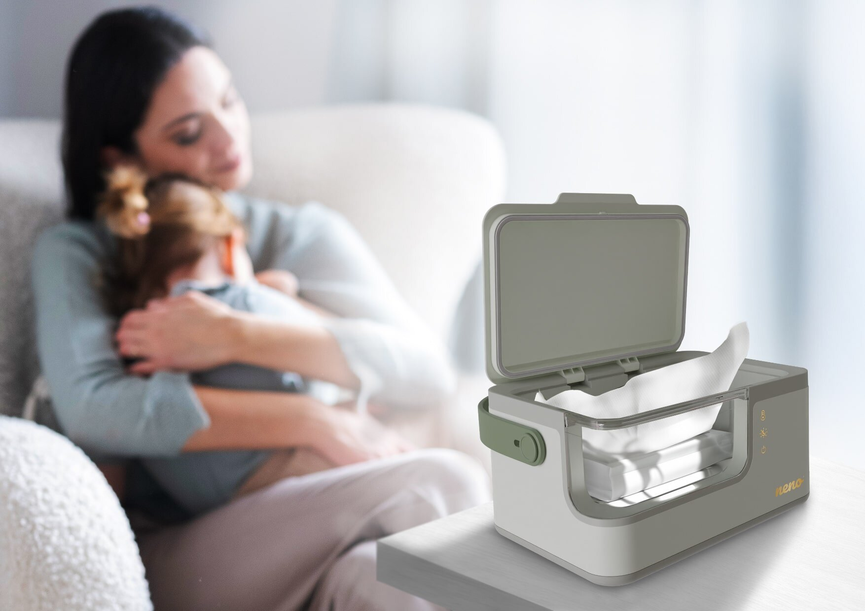 Kobieta trzyma dziecko w ramionach. Podgrzewacz do chusteczek jest na stole. Podgrzewacz jest biało-szary, z chusteczkami w środku.