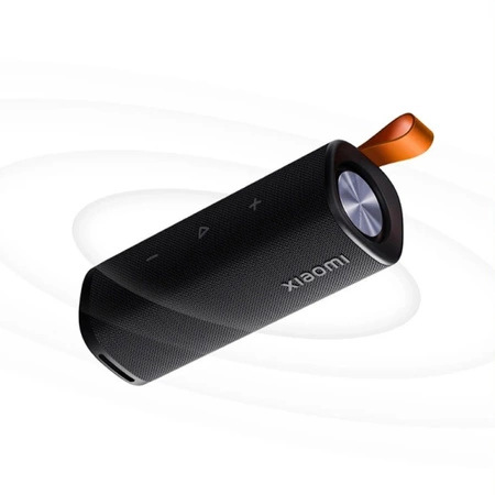 Czarny głośnik Xiaomi z pomarańczowym paskiem, przyciskami i logo Xiaomi. Na białym tle z abstrakcyjnymi okręgami.