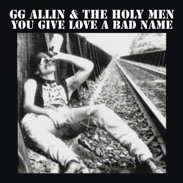GG Allin trinkt aus einer Flasche auf Bahngleisen. Schwarz-Weiß-Foto. Texte oben.