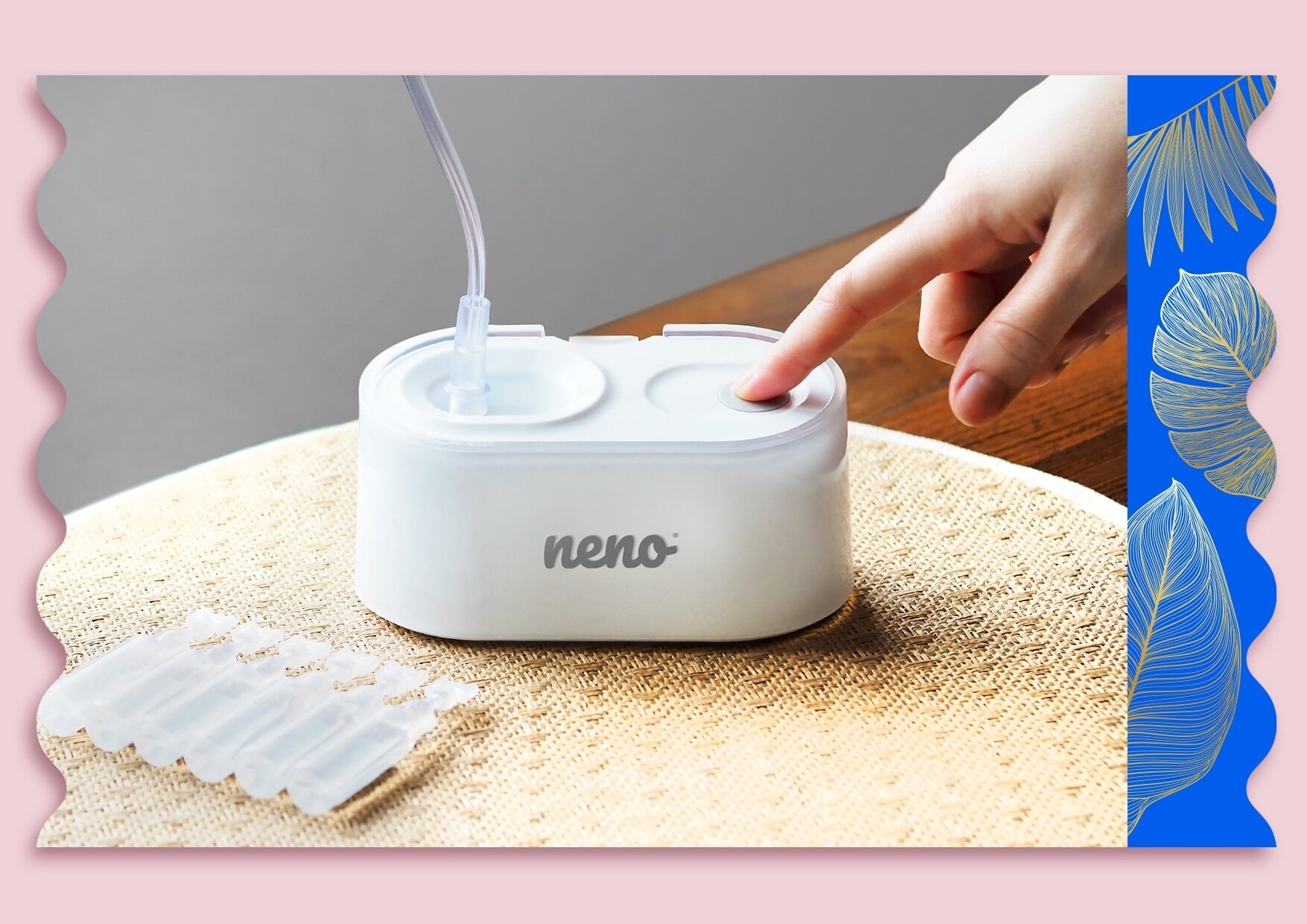 Ręka naciska przycisk na białym nebulizatorze 'neno'. Obok jednorazowe fiolki, na beżowej macie. Niebieska i złota dekoracja.