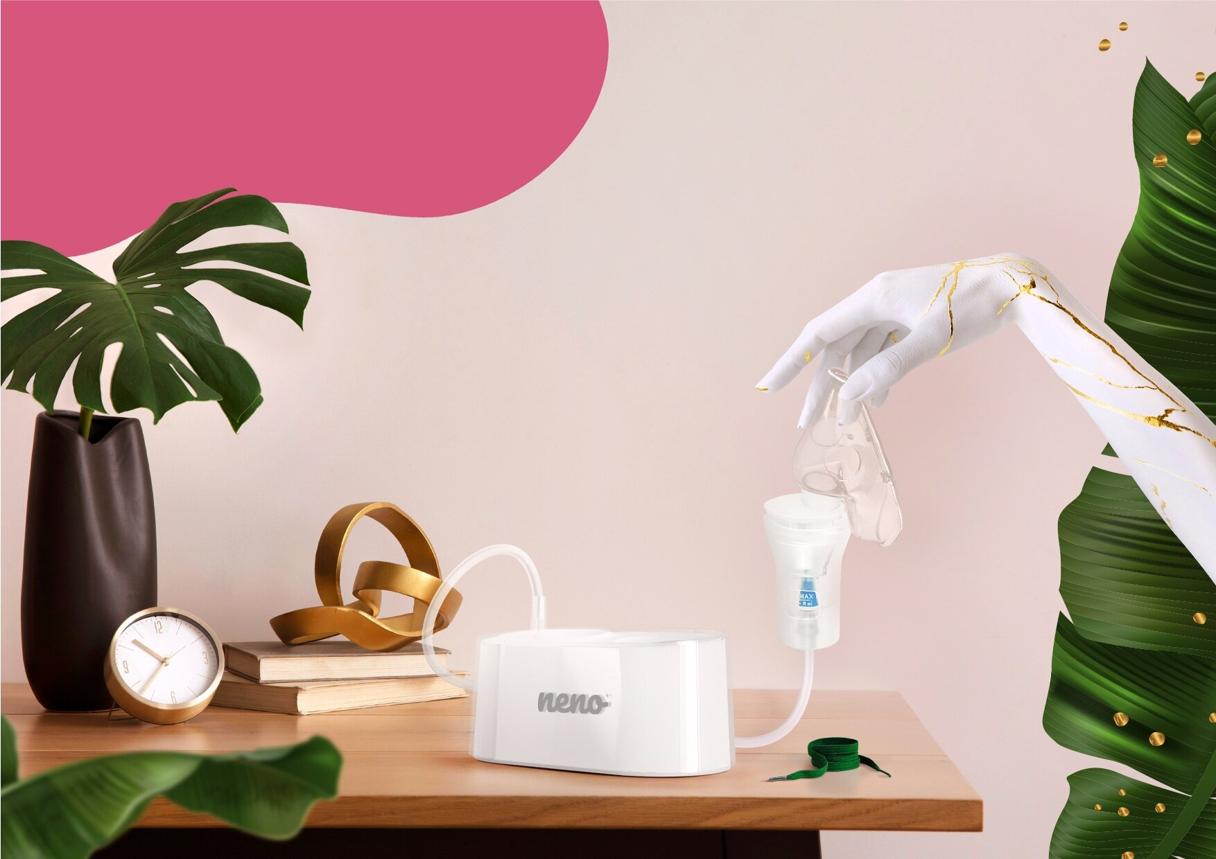 Biała dłoń, pomalowana złotymi akcentami, trzyma laktator. Biała pompa stoi na stole z dekoracjami i rośliną.