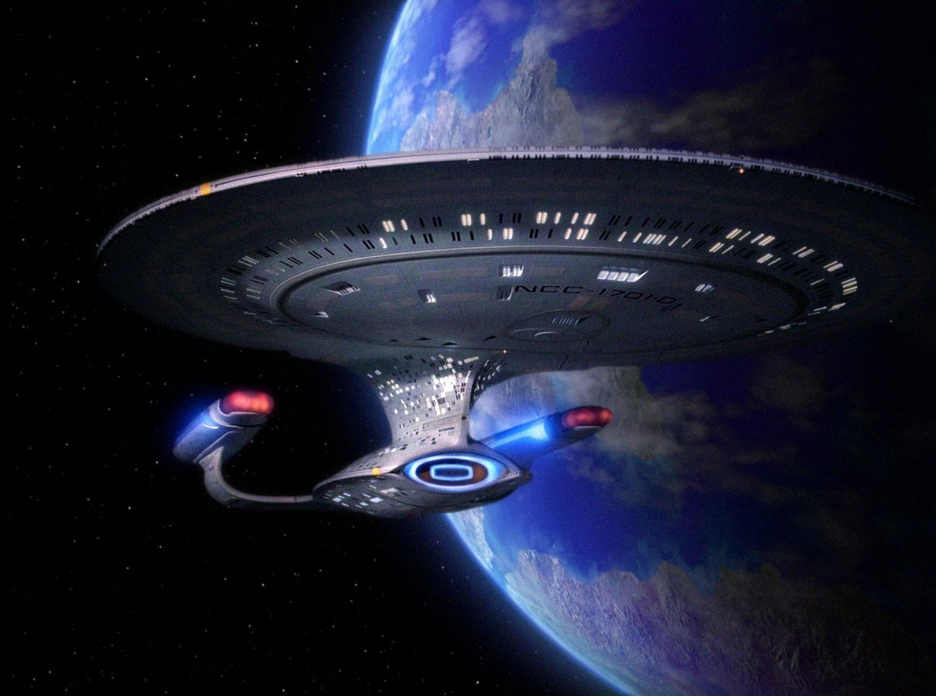 Ein Raumschiff, die USS Enterprise, im Weltraum, mit einem blauen Planeten im Hintergrund. Sterne sind sichtbar. Das Schiff hat Details.