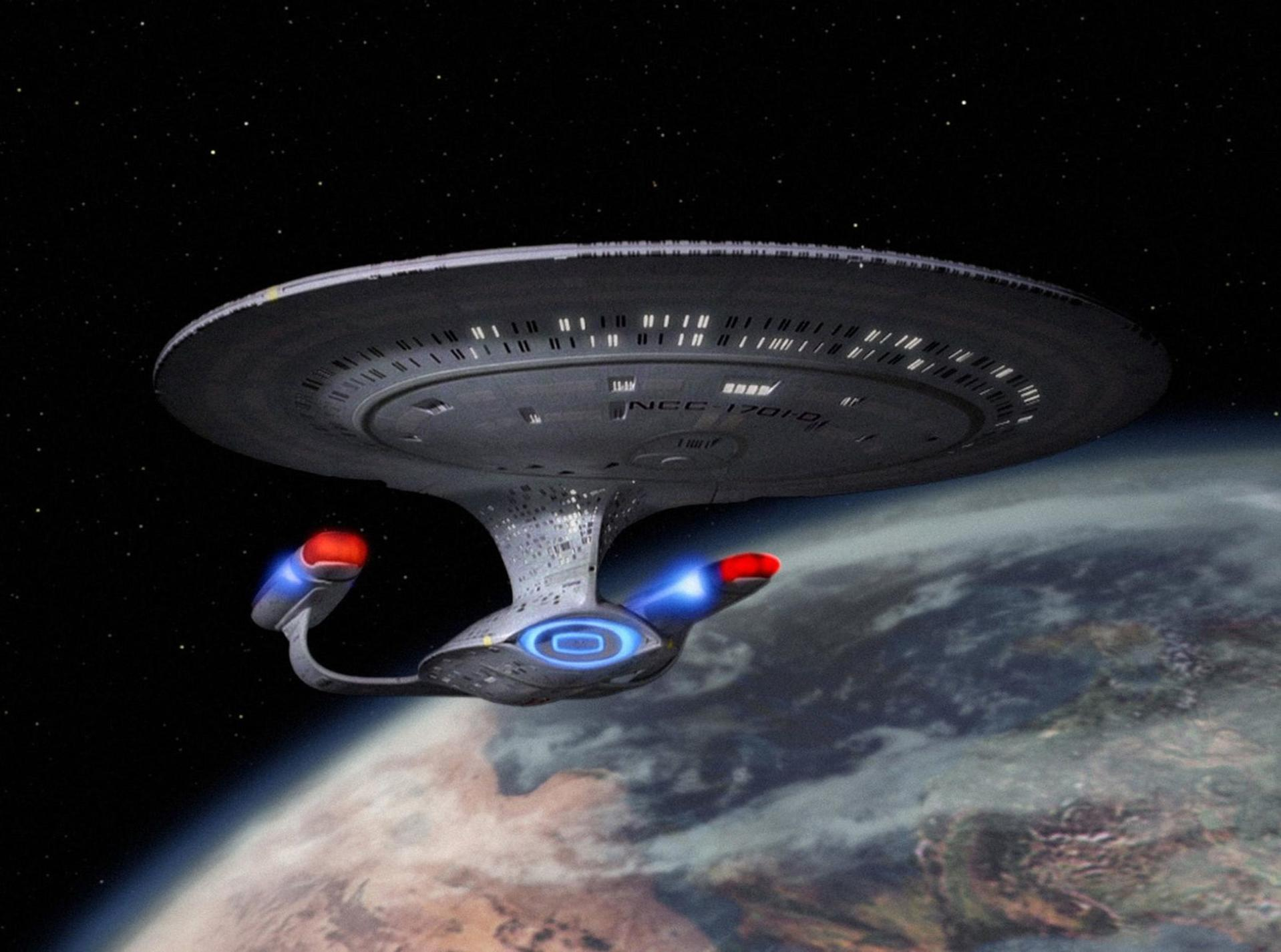 Ein Raumschiff, NCC-1701-D, fliegt über einem Planeten. Es hat einen Untertassenteil, zwei Warpgondeln und einen Sekundärrumpf.