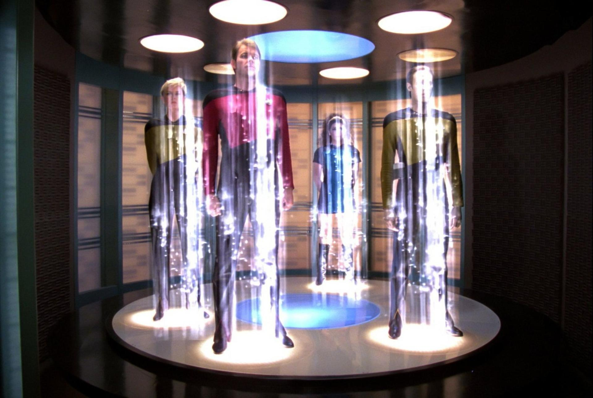 Vier Personen in Star Trek-Uniformen befinden sich in einem Transporterraum, umgeben von Lichtstrahlen. Die Szene ist futuristisch und gut beleuchtet.