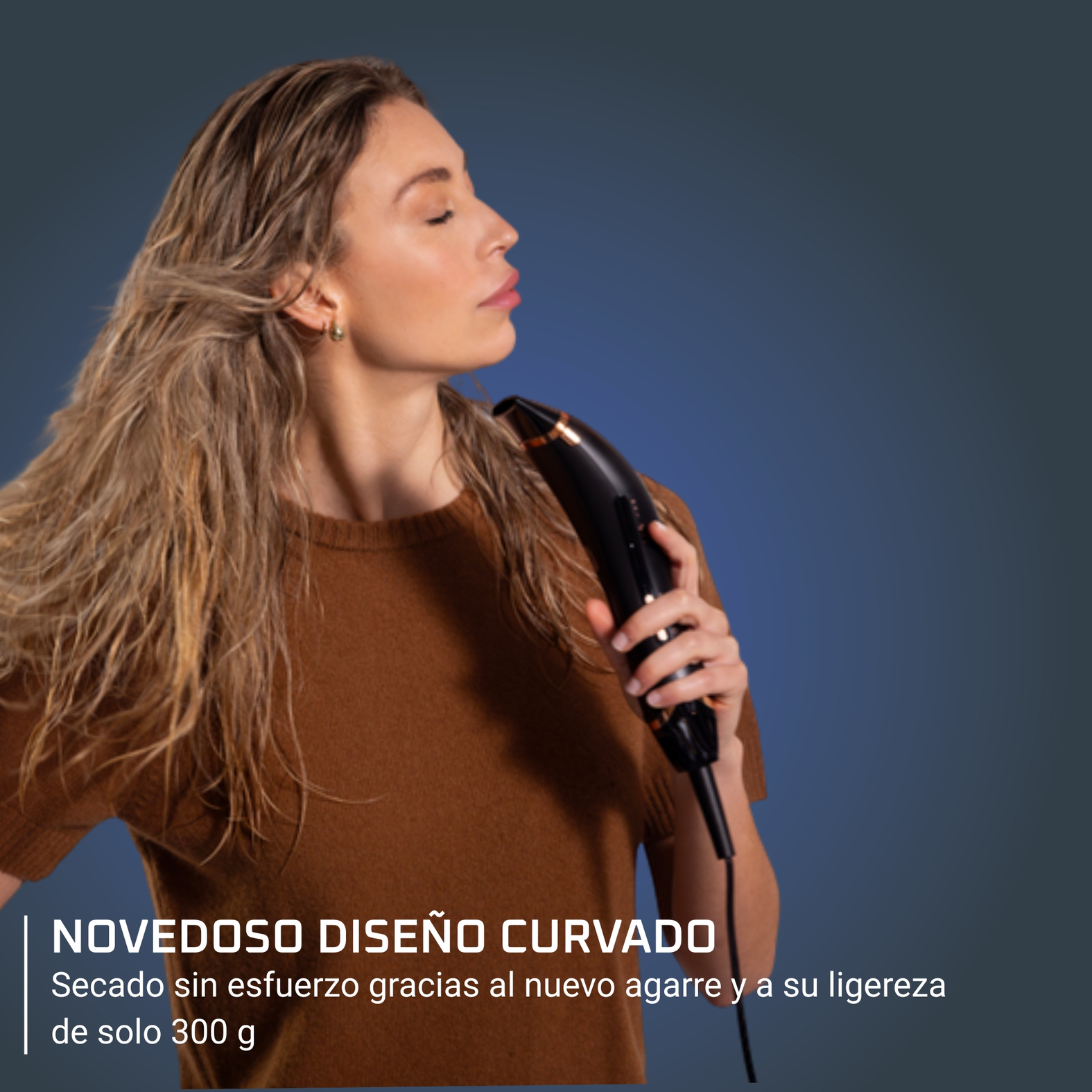 Una mujer se seca el pelo con un secador de pelo negro y dorado, con los ojos cerrados. Lleva un suéter marrón, sobre un fondo azul.