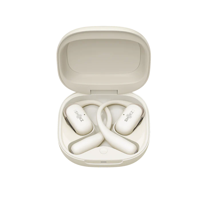 Estuche crema abierto con auriculares blancos dentro. Los auriculares tienen el logo Shokz. La parte superior del estuche está abierta y vacía.