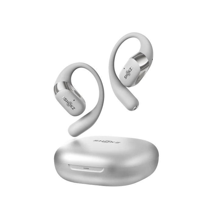 Auriculares Shokz blancos y estuche de carga sobre fondo negro. Los auriculares tienen un diseño curvo con la marca visible.
