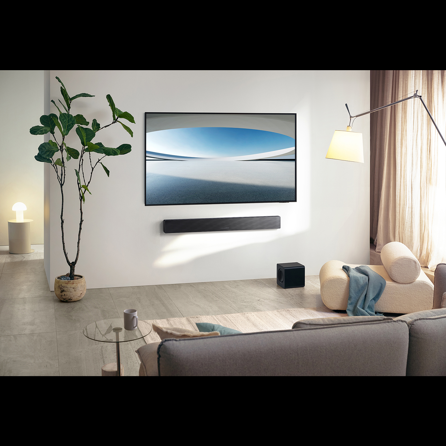 Salón moderno con un televisor grande. Incluye una barra de sonido, un subwoofer, un sofá y una planta en maceta. También se ven una lámpara y cortinas.