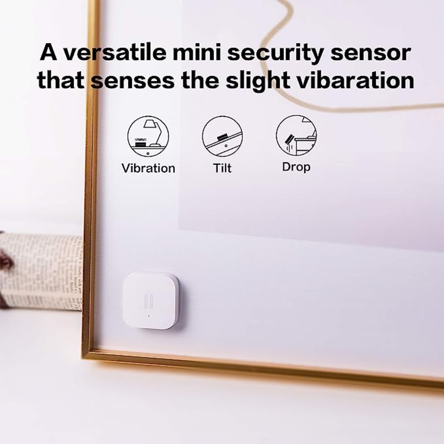 White square security sensor on a white wall in a golden frame, with illustrations of vibration, tilt, and drop.